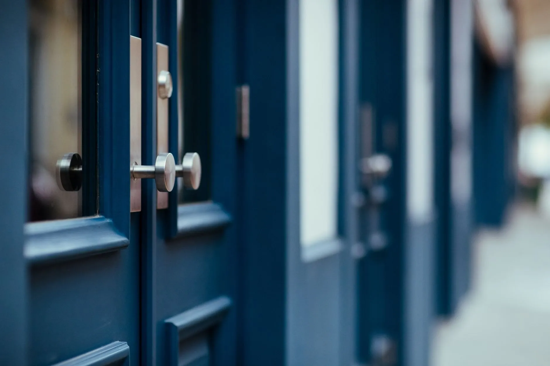 A row of dark blue panelled doors with steel handles