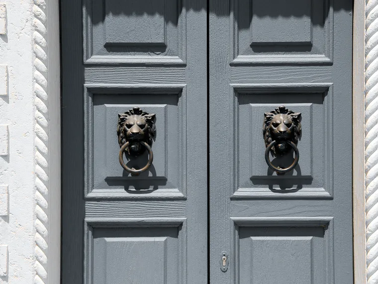 A pair of painted doors with cast knockers and rim cylinders.