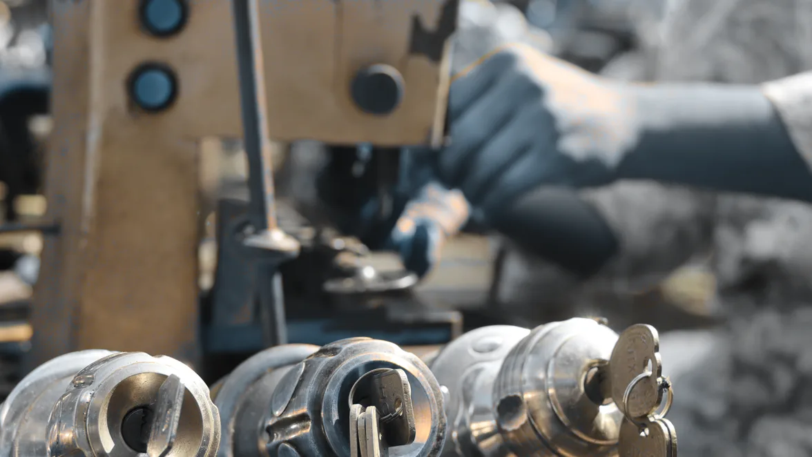 A key being cut on the bench, three cylinders waiting to be pinned.