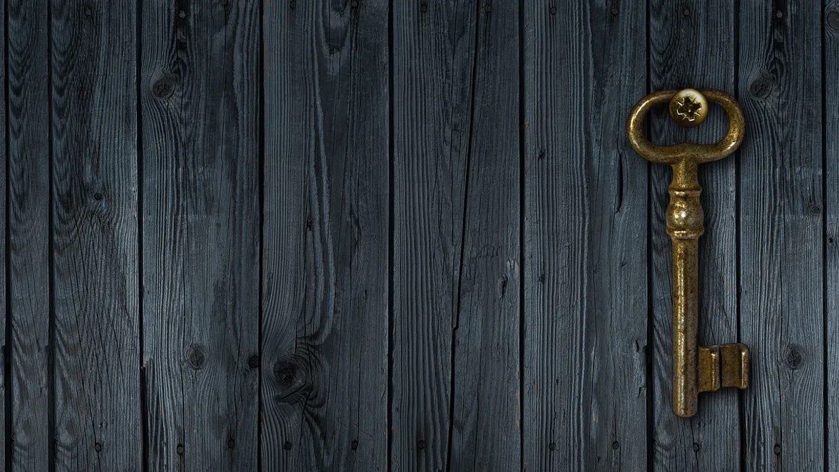A bit key hanging on the boards of an old door.